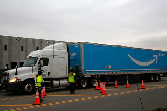 An Amazon Prime truck passes by two women controlling traffic outside an Amazon fulfillment center, on Staten Island, in New York on March 19th.